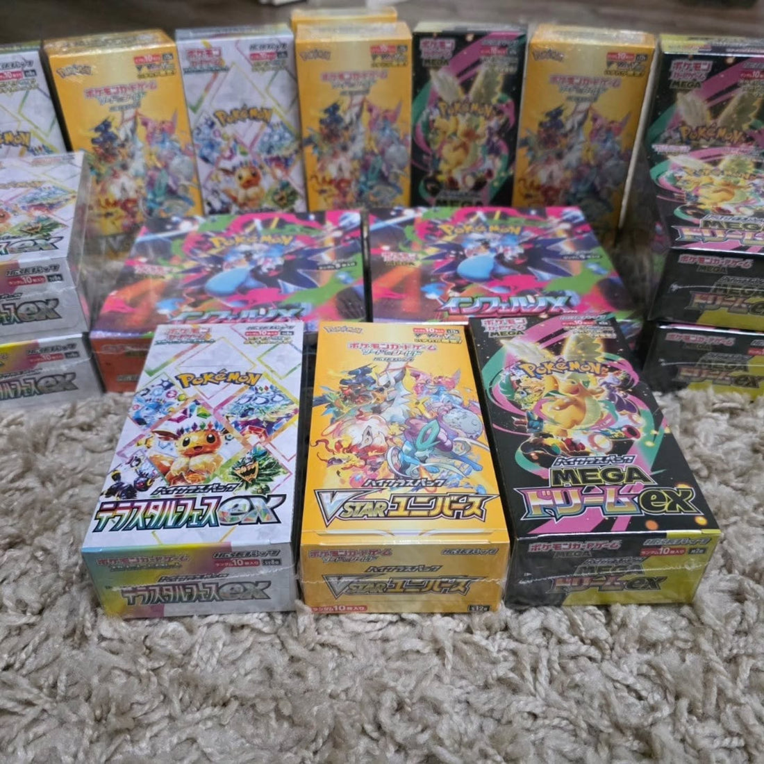 Stapels Japanse booster boxen, waaronder Terastal Festival ex, VSTAR Universe, Mega Dream ex en Inferno X